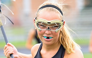 Teen girl playing lacrsse with blue mouthguard