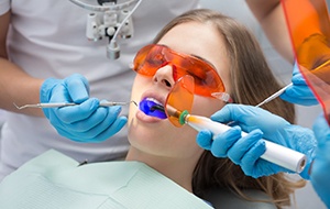 Dental team hardening the resin of a tooth-colored filling