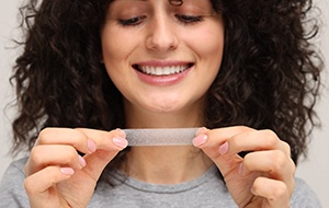 Woman holding a teeth whitening strip