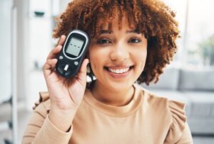 Smiling woman holding blood glucose monitor